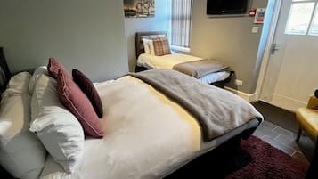 A hotel room with two beds, a television, a painting on the wall, and a window with blinds.