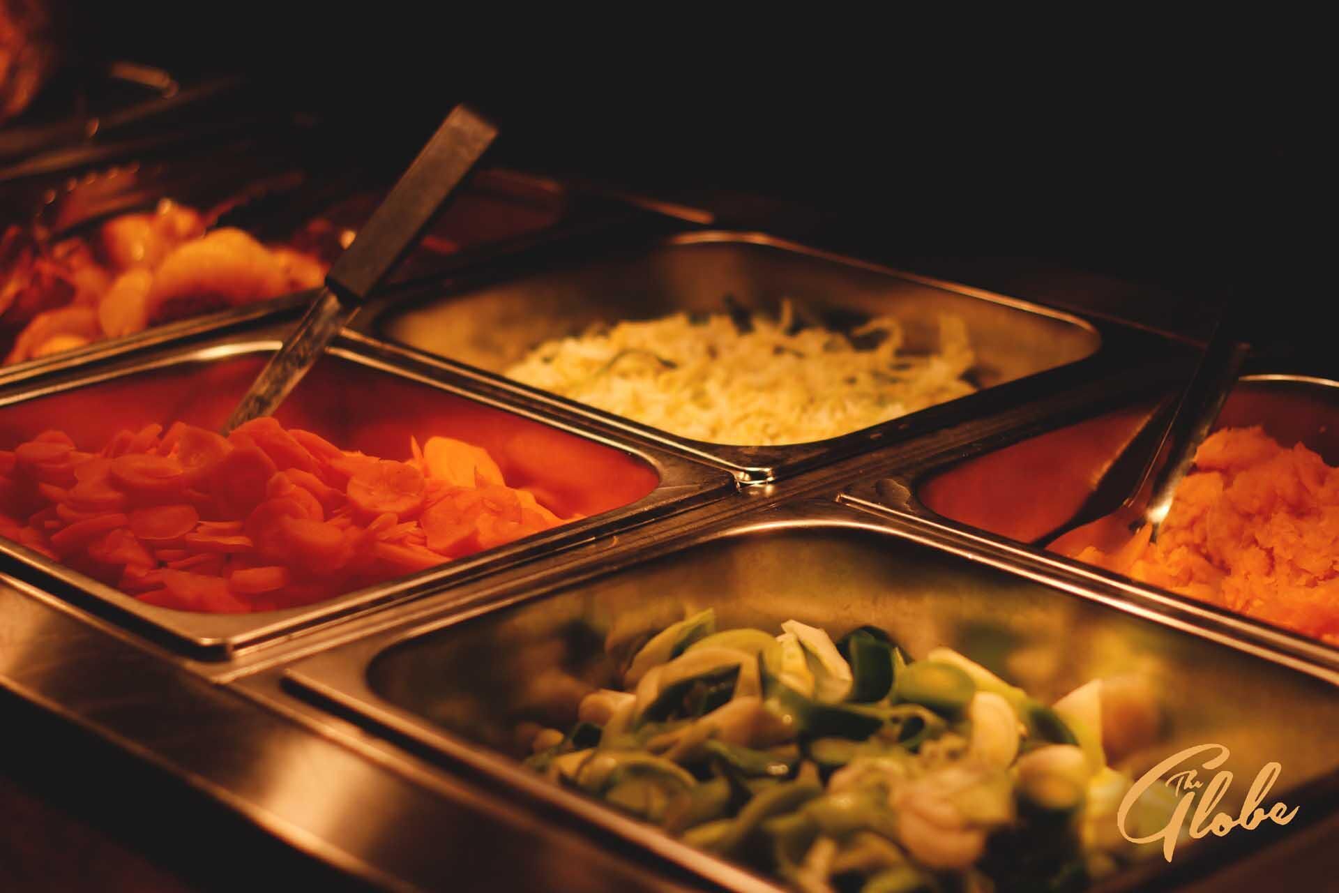 Ein Buffet mit verschiedenen Speisen in Metallservierplatten.