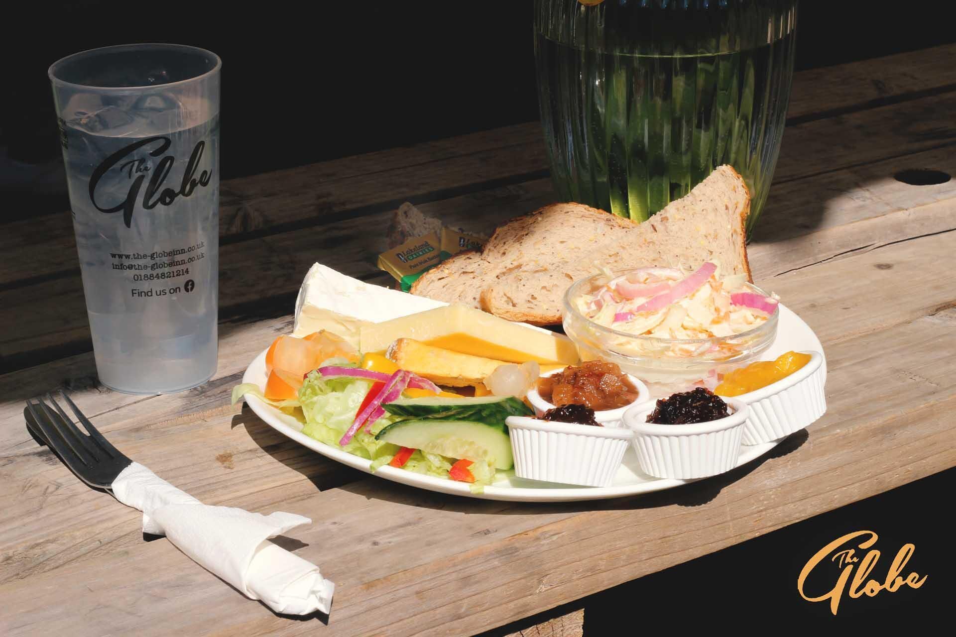 A meal with bread, cheese, salad, and dips on a wooden table.
