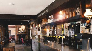 A bar area with wooden shelves, a counter, and various bottles and glasses. - The Globe Inn (Tiverton)