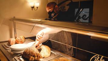 A buffet setup with various dishes, including roasted meat and bread, in a well-lit kitchen area.