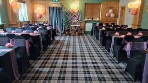 A banquet hall with checkered flooring, tables with pink sashes, and balloons. - Gilpin Bridge Inn (Kendal)