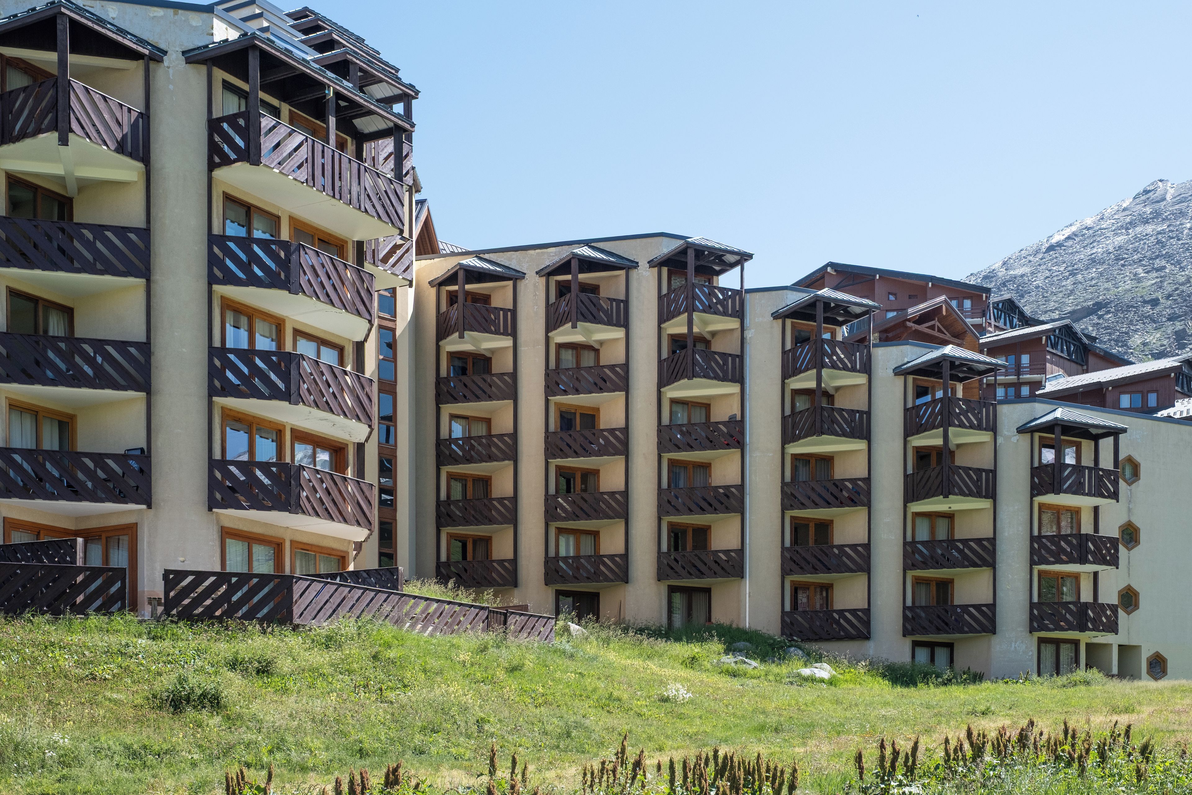 Ein mehrgeschossiges Hotel mit Balkonen vor einer Bergkulisse.