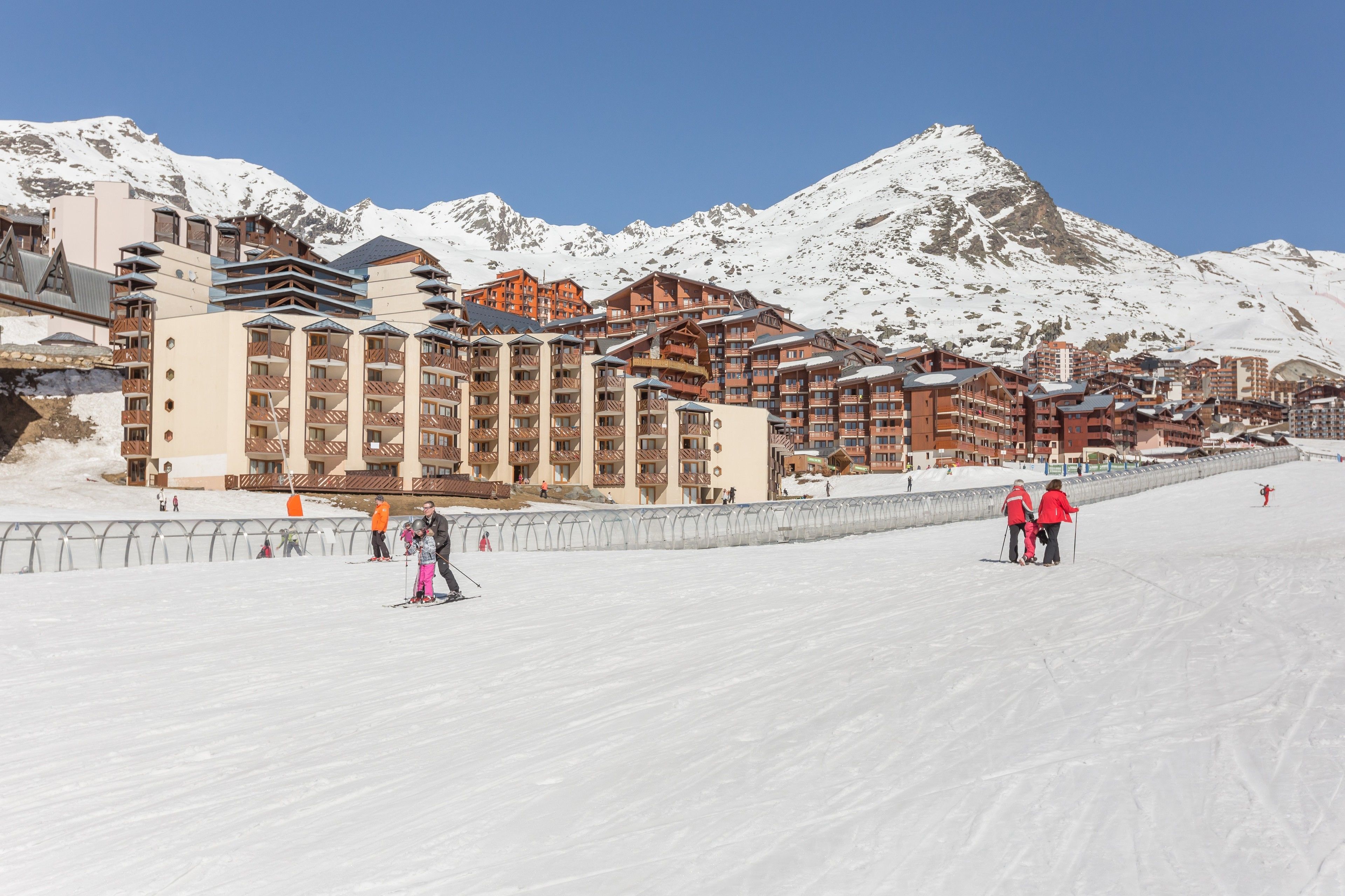 Una stazione sciistica con edifici a più piani, piste da sci e montagne innevate sullo sfondo.