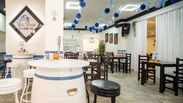 A restaurant interior with a central bar area, multiple seating arrangements, and decorative paper lanterns. - Hostal Valdepeñas by Bossh Hotels (Valdepenas)