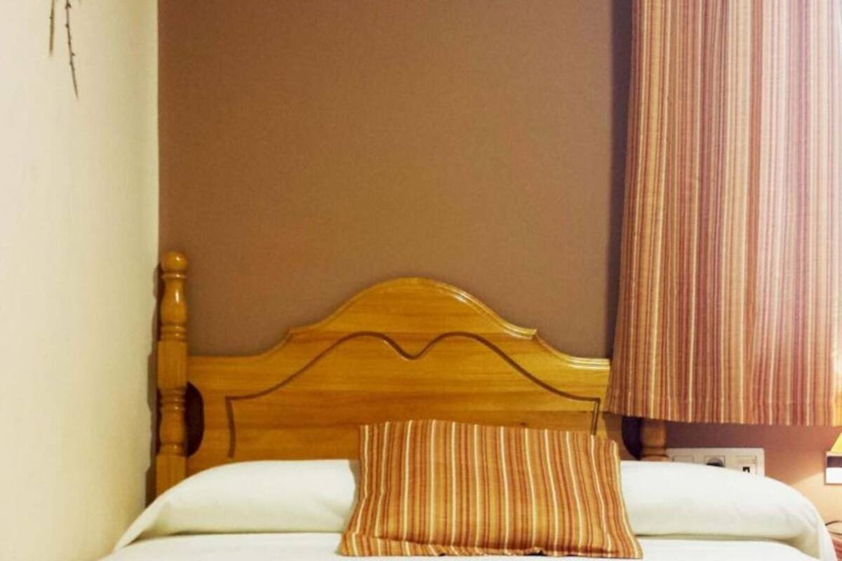 A bed with a wooden headboard, a striped pillow, and a blue blanket.