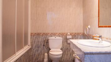 A bathroom with a toilet, sink, and shower.