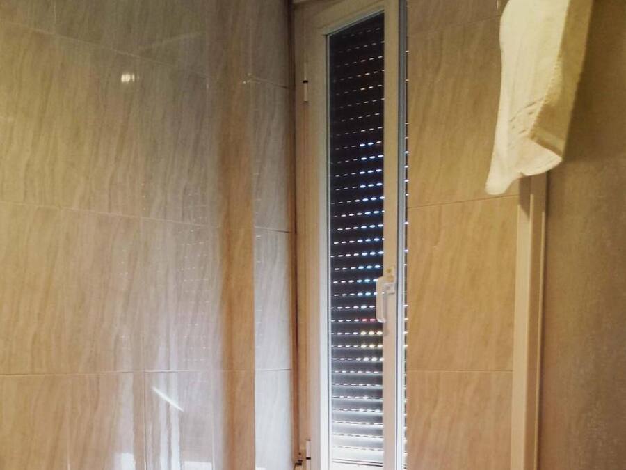 A bathroom with a bidet, toilet, and a window with blinds.