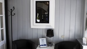 A room with two black armchairs, a white side table with a framed certificate, a black lamp, and a framed picture on the wall. - Hostal Valdepeñas by Bossh Hotels (Valdepenas)
