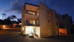 A two-story residential building with a balcony on the upper floor, a garage, and a driveway. - Villa Mar Colina (Yeppoon)