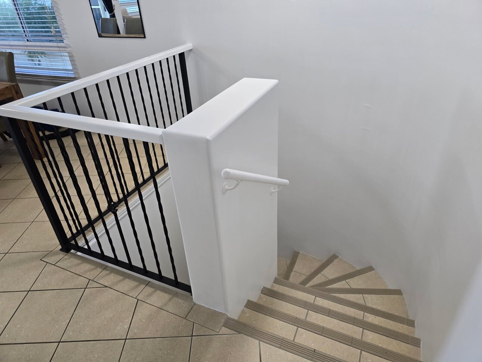 A staircase with a white handrail and black balusters, leading to a landing with a white door.