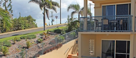 A two-story building with a swimming pool, outdoor seating, and a balcony with a railing.