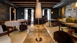 Un restaurante con una columna central, mesas, sillas y piso de piedra.