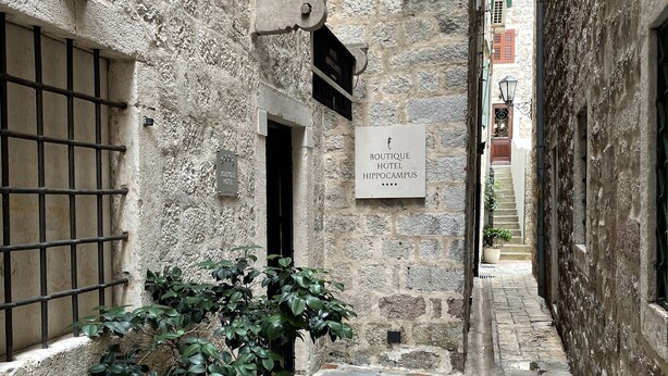 Un estrecho callejón de piedra con un cartel del Hotel Boutique Hippocampus.