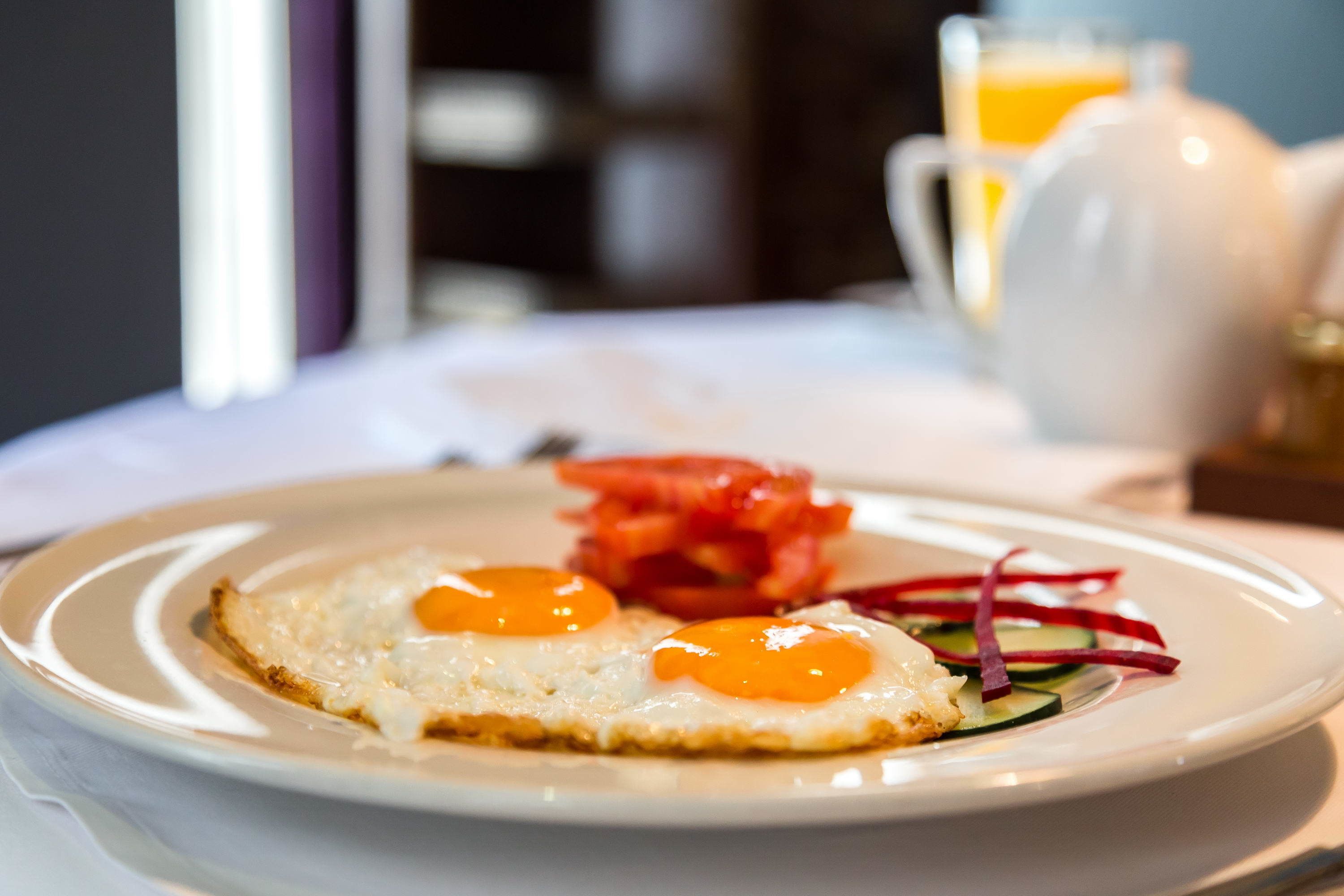 A breakfast plate with eggs, vegetables, and a glass of orange juice.