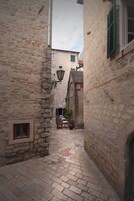 Un estrecho callejón de piedra con una mesa y sillas dispuestas, lo que sugiere un área de comedor.