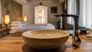 Un lavamanos de madera en una habitación de hotel, con una cama, lámparas de noche y una ventana.