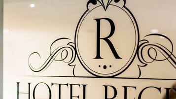 Une enseigne d’hôtel portant le nom « HÔTEL REGI » et surmontée d’un grand emblème en forme de « R ».