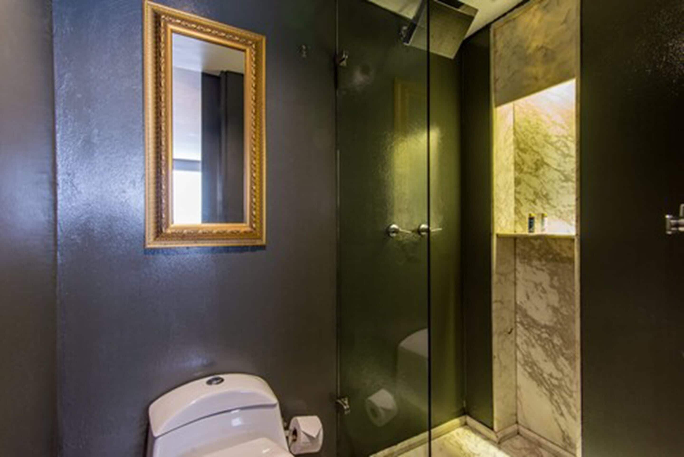 Un baño con inodoro, cabina de ducha de vidrio y pared revestida de mármol.