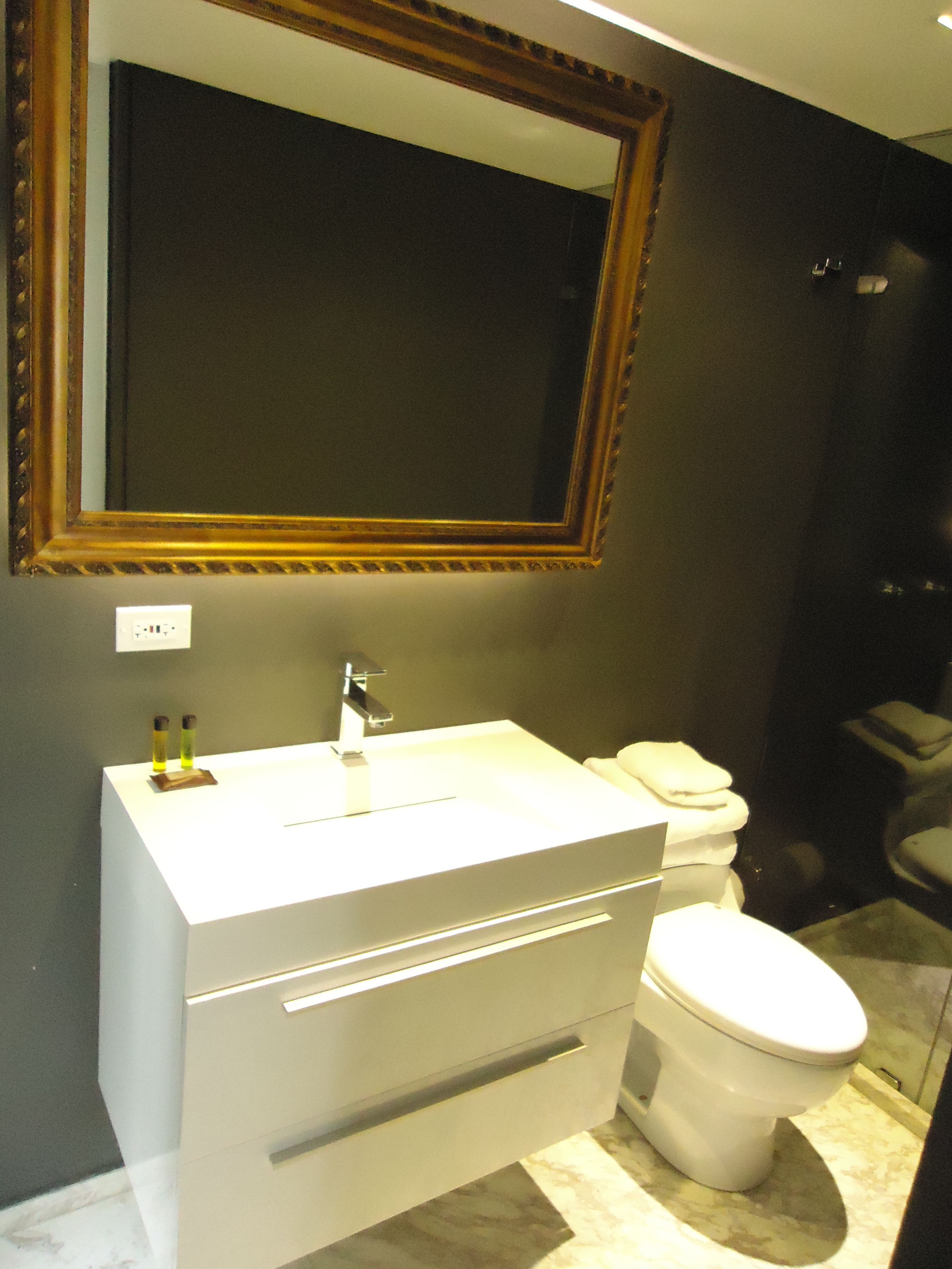 A bathroom with a white vanity, a mirror, and a toilet.