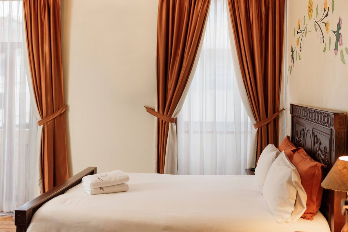 Una habitación de hotel con cama, cortinas y un adorno en la pared.