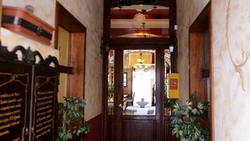 A hallway with a stone floor, wooden doors, and a chandelier.