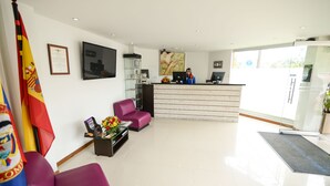 A reception area with a reception desk, a flag, a framed certificate, and a painting on the wall.