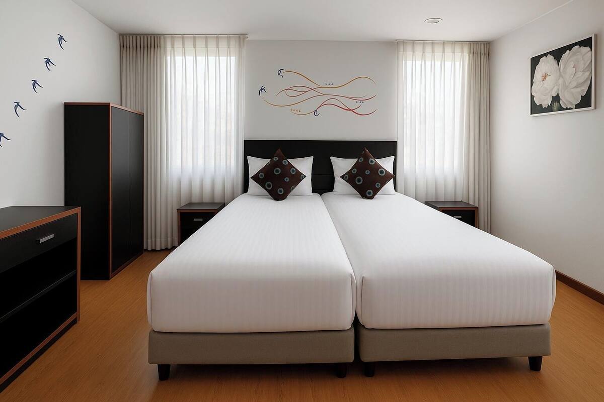 A double bed with two pillows, a nightstand, a wardrobe, and a wall with abstract art and a flower painting.