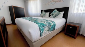 A hotel room with a large bed, a nightstand, a wardrobe, and a window with curtains.