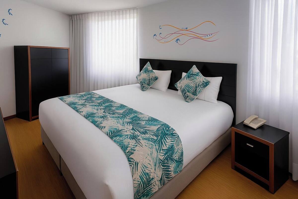 A hotel room with a large bed, a nightstand with a phone, a wardrobe, and a wall with a decorative design.
