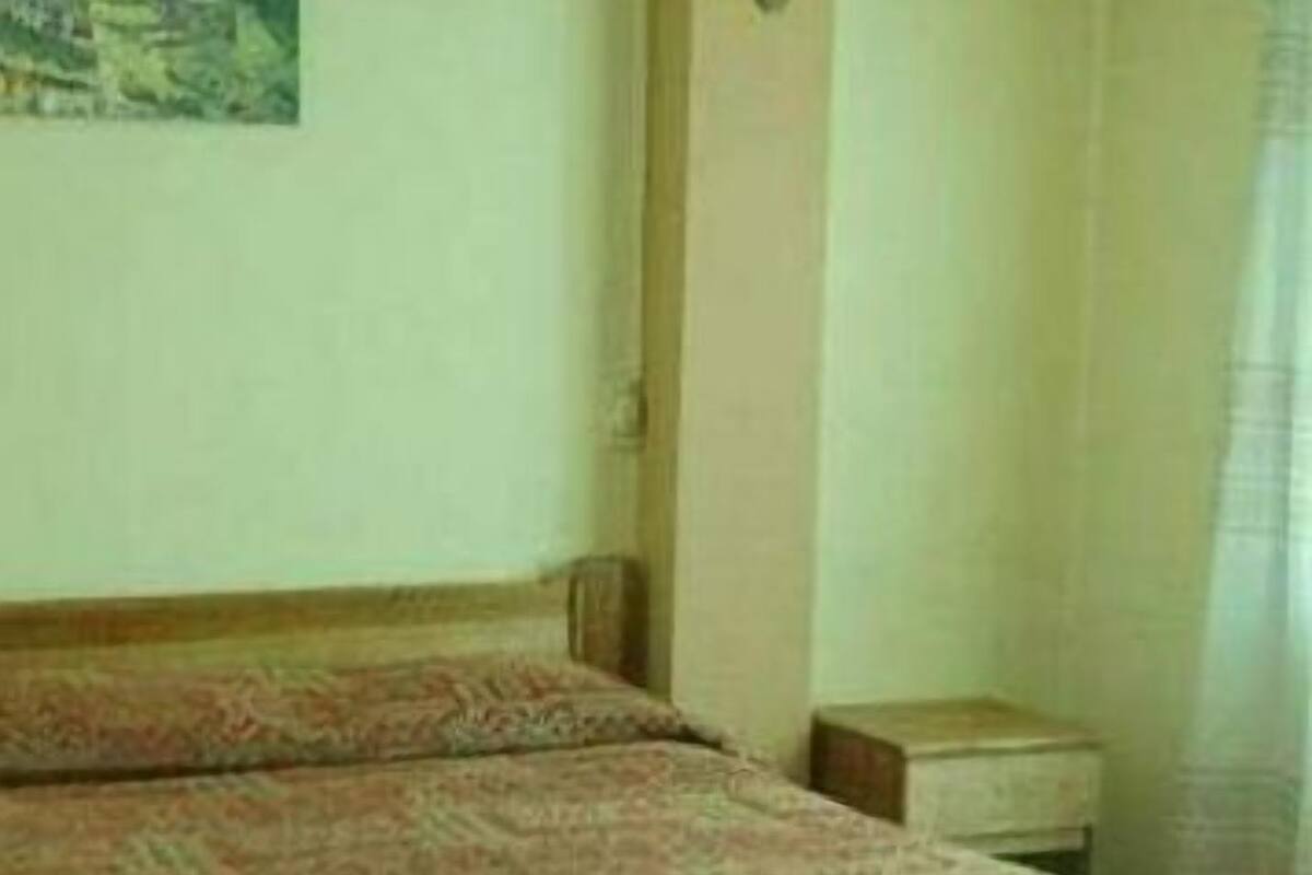 Un dormitorio con cama, mesita de noche y un cuadro en la pared.