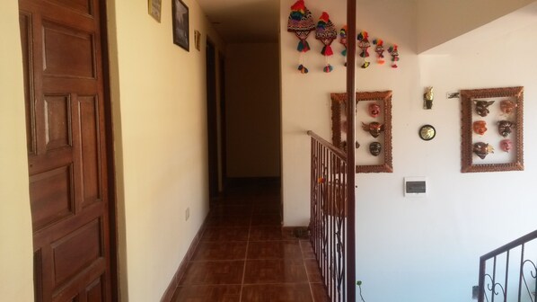 A hallway with a wooden door, a staircase, and decorative masks on the wall.