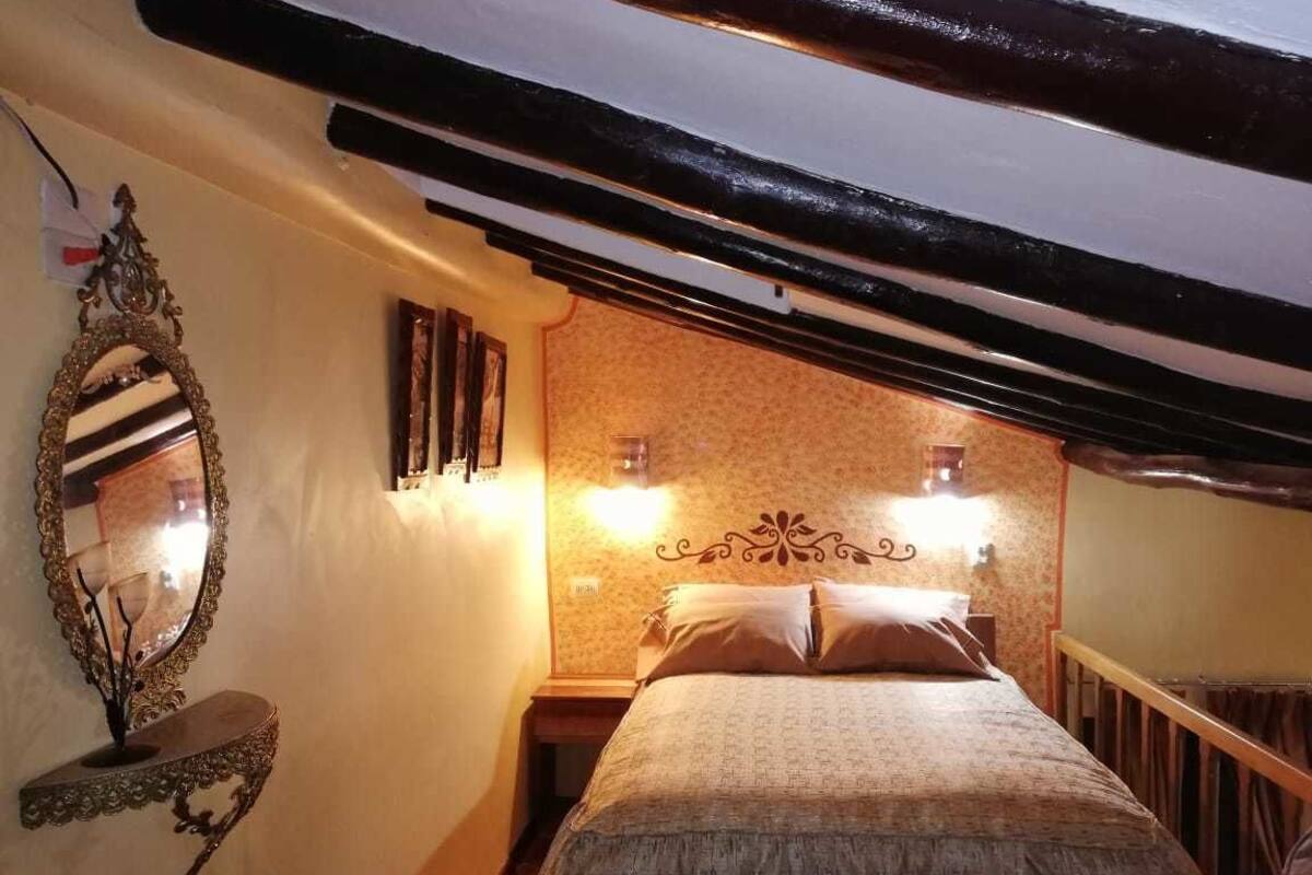 Un dormitorio con una cama, un espejo montado en la pared y dos apliques.