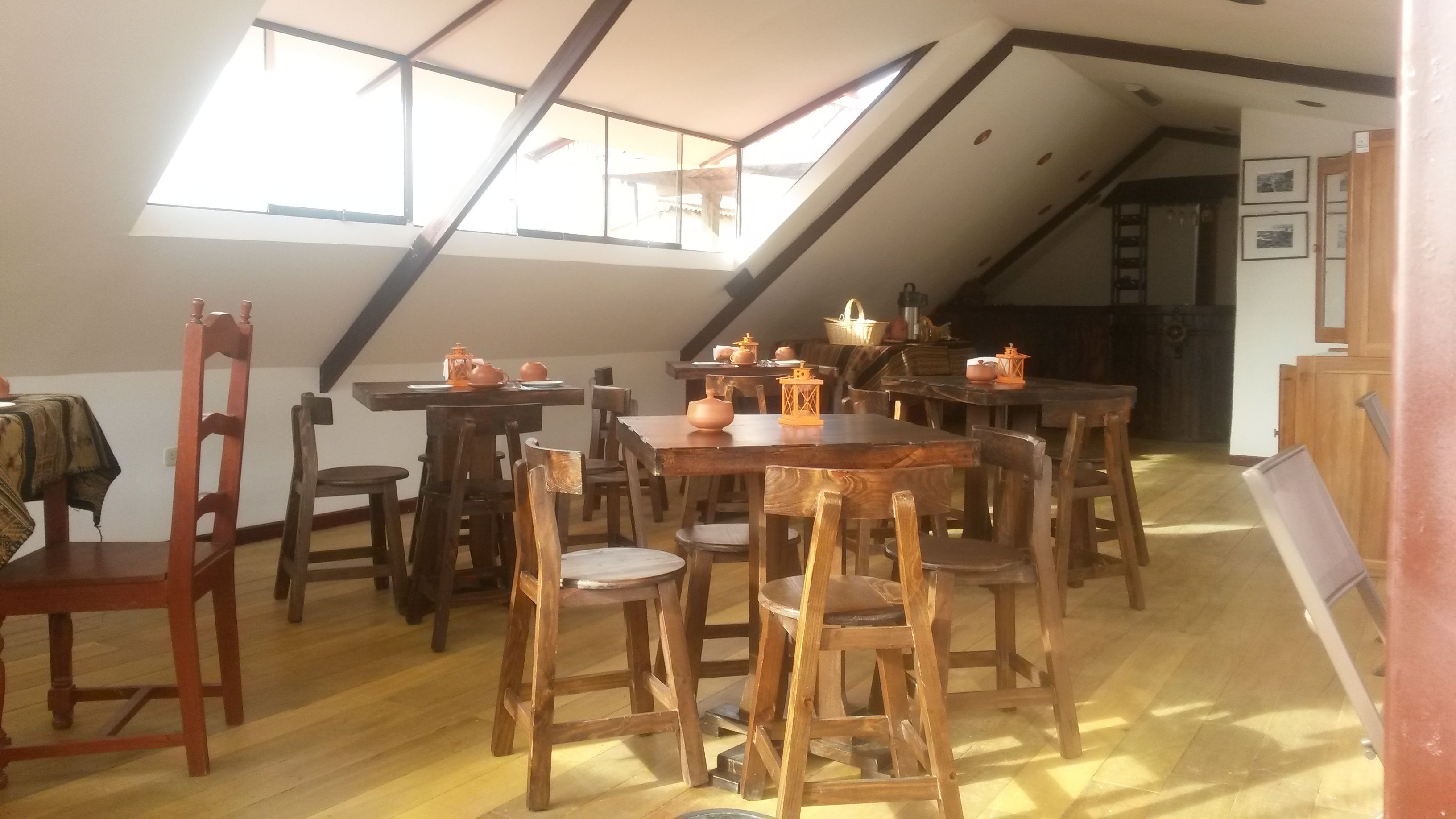 A dining area with wooden tables and chairs, a sloped ceiling, and skylights.