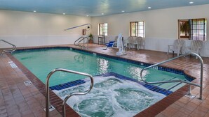 Une piscine intérieure dotée d’un jacuzzi, d’un sol carrelé et de rampes de sécurité.