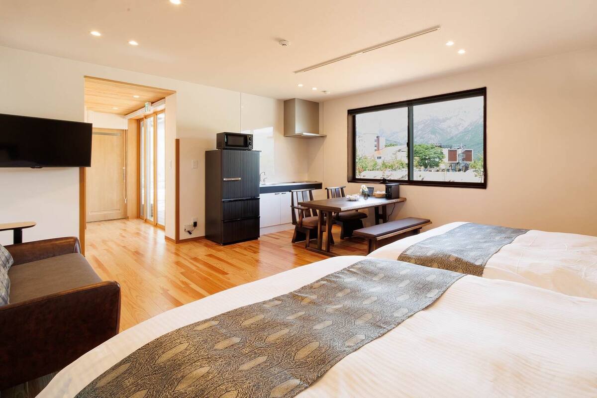 Habitación de hotel con dos camas, un comedor, una cocina y un televisor.