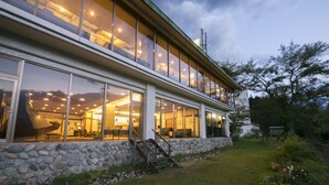 A modern building with large windows, a stone facade, and a staircase leading to an upper level. - Hakuba Highland Hotel (Hakuba)