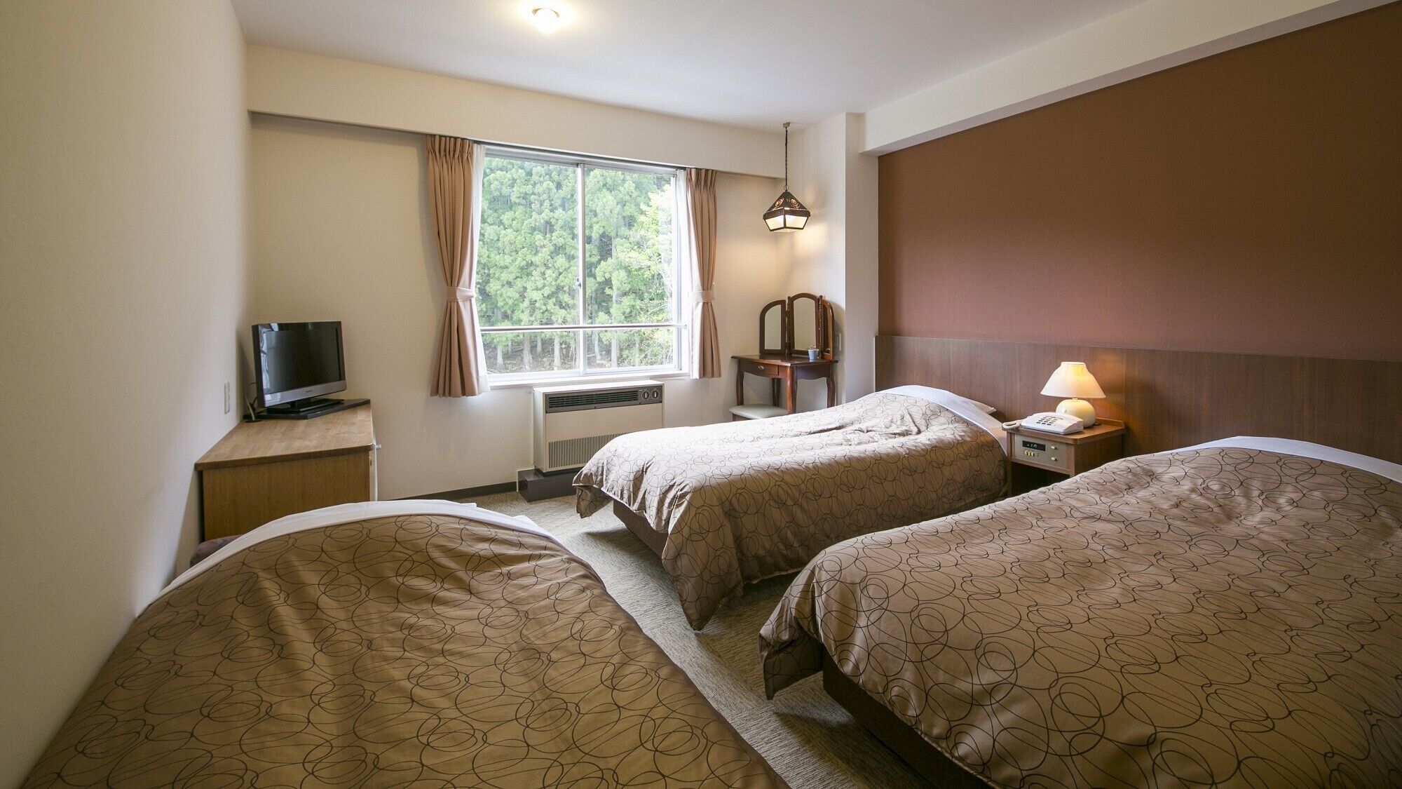 Quarto de hotel com duas camas, televisão, secretária, janela com cortinas, espelho e abajur.
