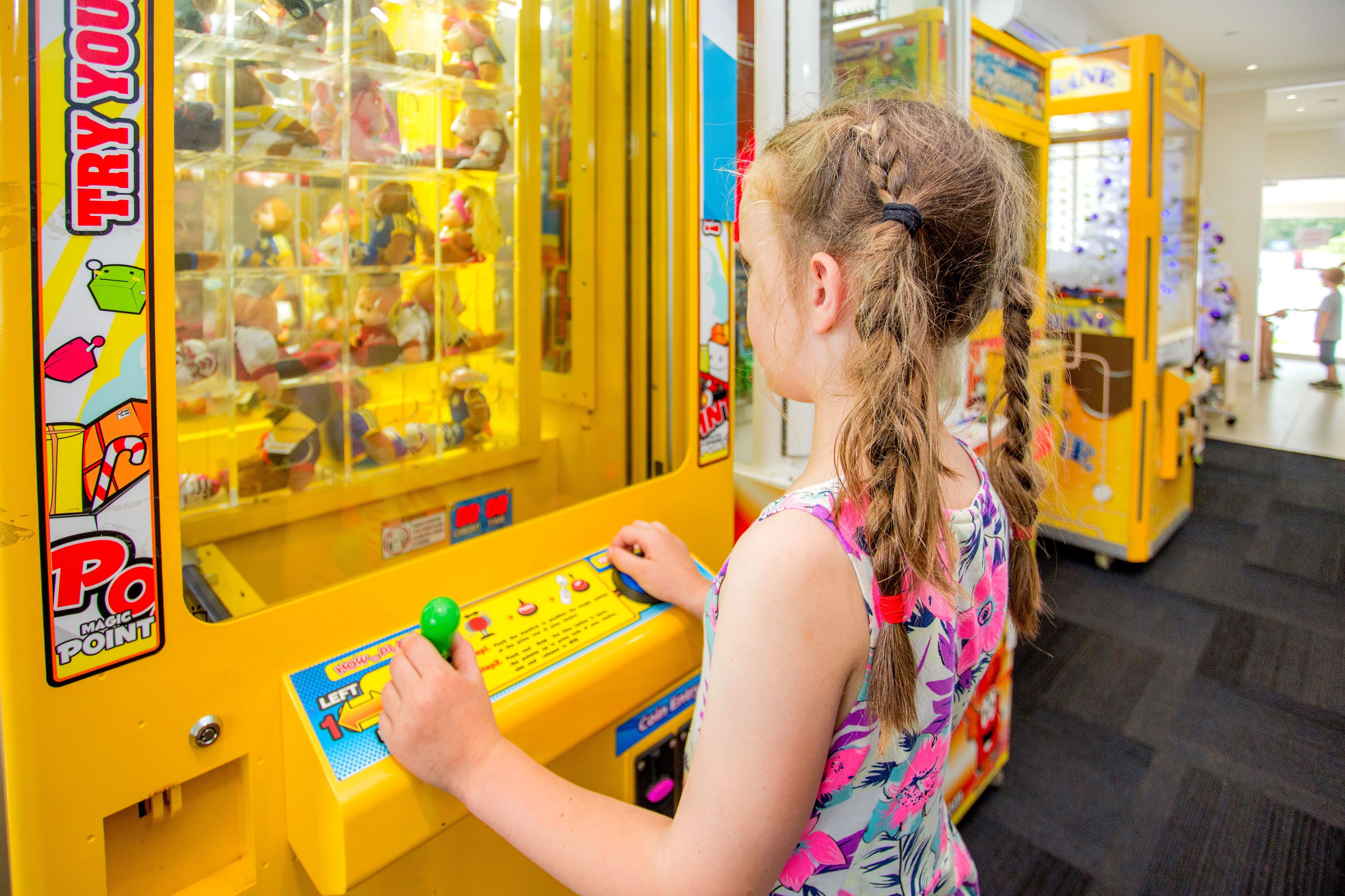 Niño jugando a un juego en una máquina recreativa amarilla con el rótulo 