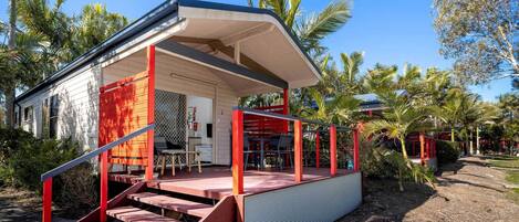 A modern house with a covered porch, a staircase, and a view of the surrounding tropical garden.