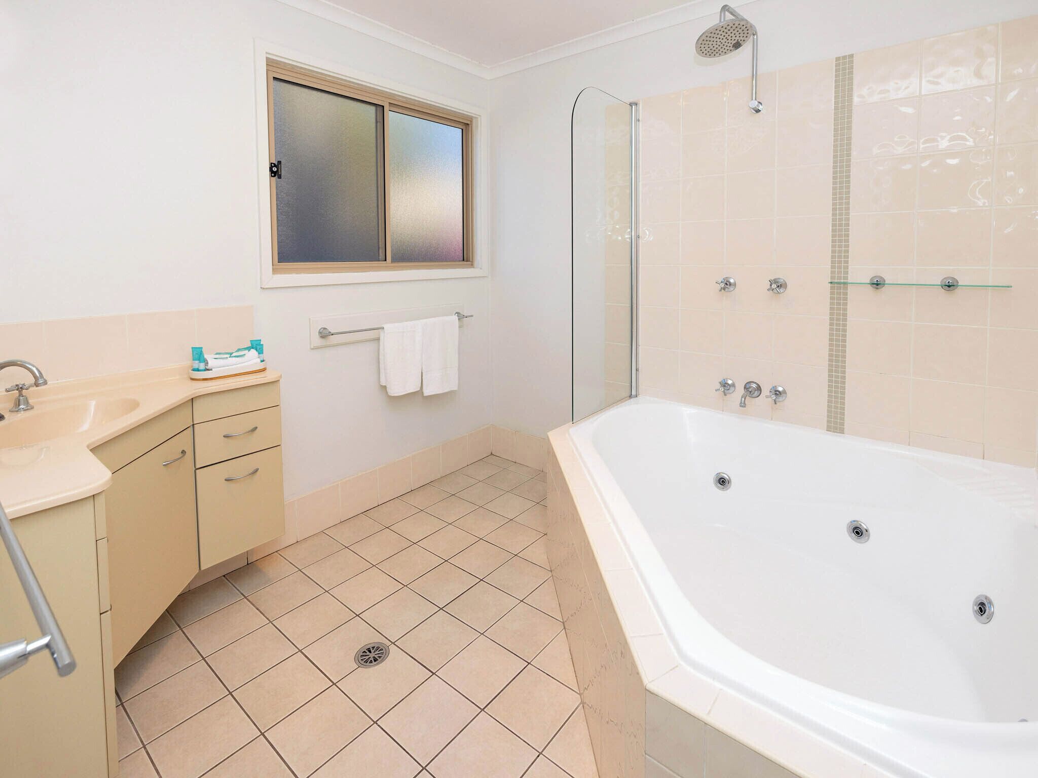 Un baño con bañera, ducha, lavamanos y ventana.