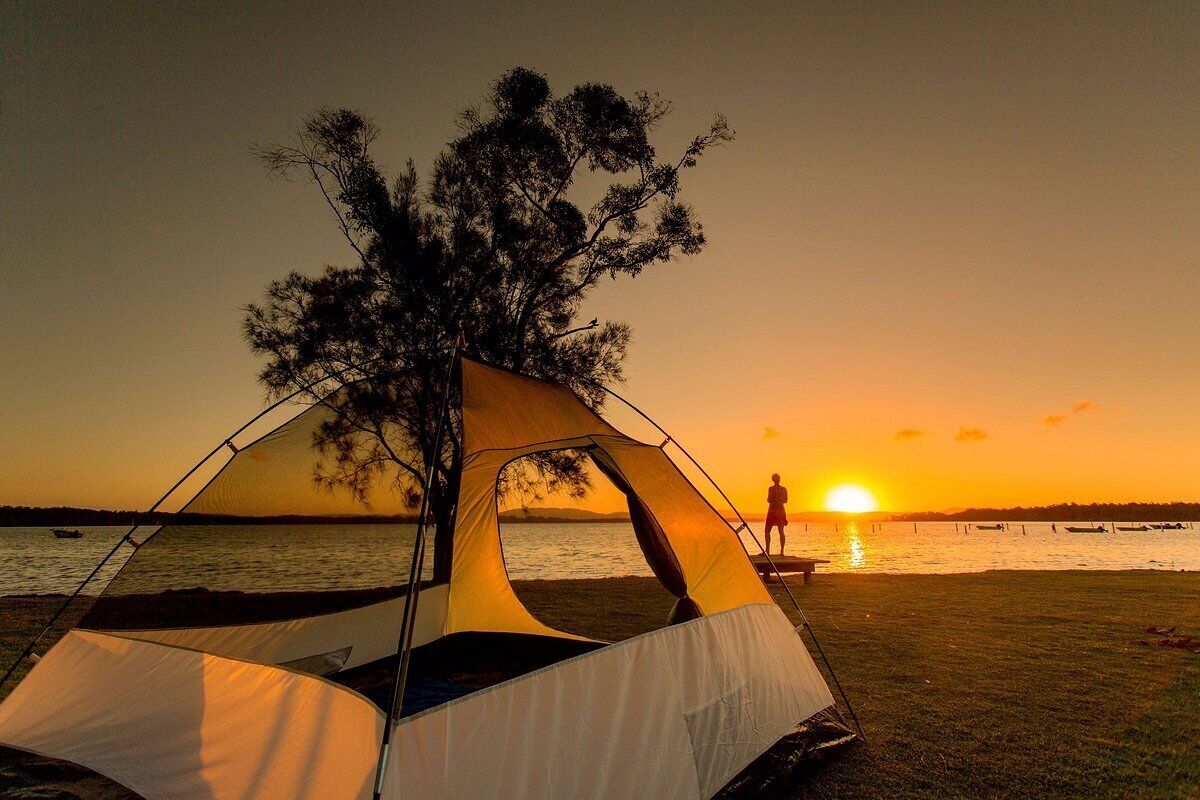 A tent set up near a body of water at sunset.