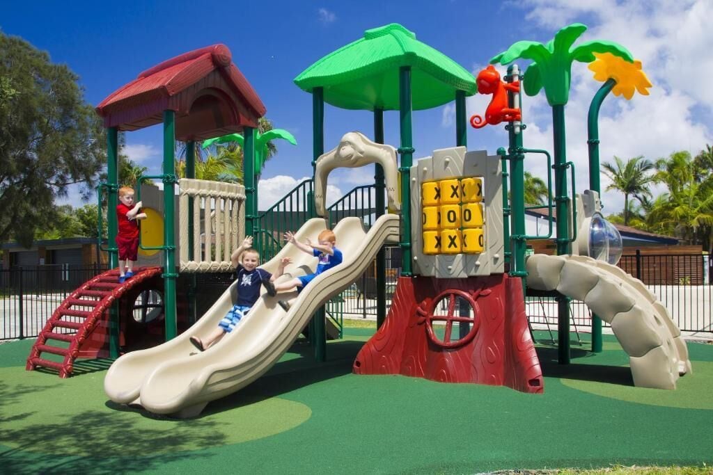 A playground with slides, climbing structures, and a red-roofed shelter.