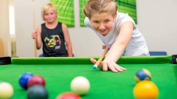A pool table with balls and a person leaning over it.