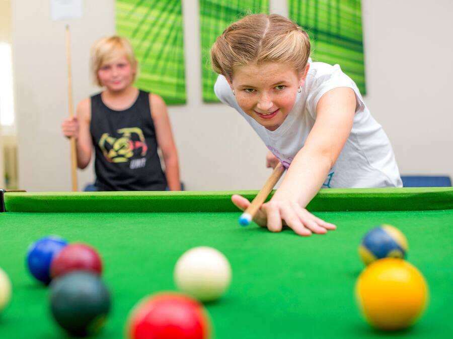 A pool table with balls and a person leaning over it.