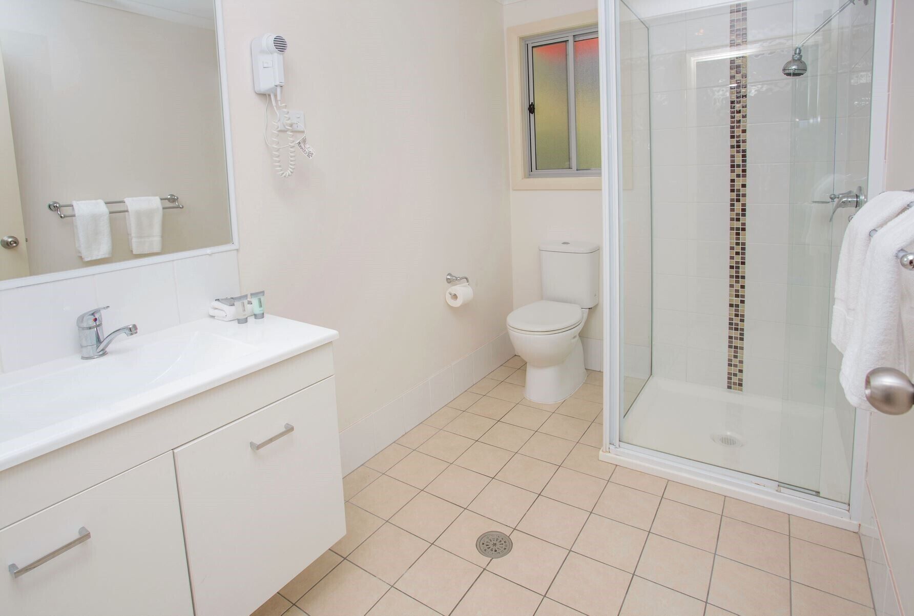 Een moderne badkamer met een witte wastafel, een douchecabine met glazen wanden en een toilet.