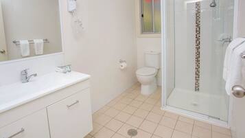 Een moderne badkamer met een witte wastafel, een douchecabine met glazen wanden en een toilet.
