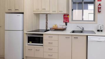 A compact kitchen with a refrigerator, microwave, stove, sink, and dishwasher.