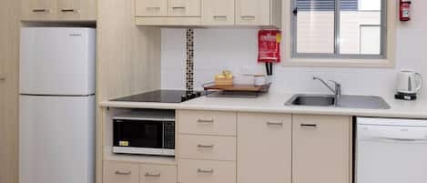 A compact kitchen with a refrigerator, microwave, stove, sink, and dishwasher.