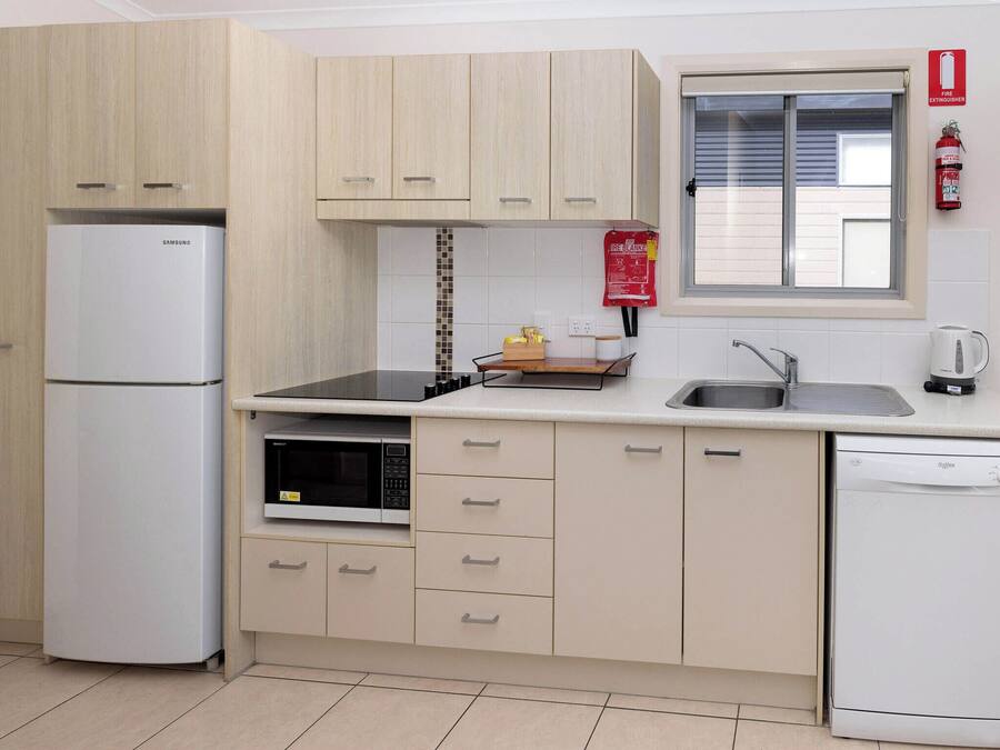 A compact kitchen with a refrigerator, microwave, stove, sink, and dishwasher.